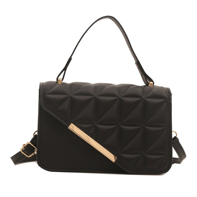 Black quilted handbag with gold accents on a white background